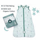 Nintara Baby sleep sack laid flat beside its gift box packaging. Text highlights 1.5 TOG rating and 100% soft organic cotton. Decorative green leaves styled around the product on a white surface.