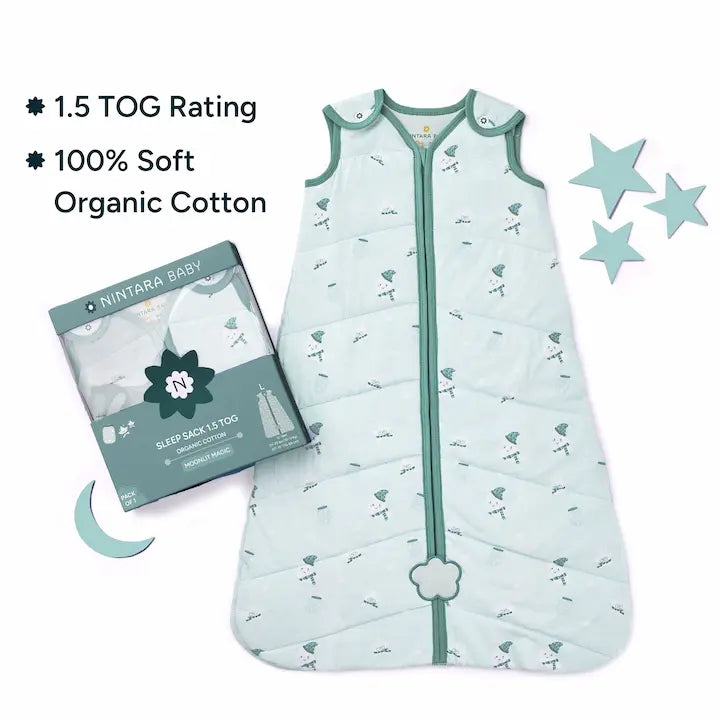 Nintara Baby sleep sack laid flat beside its gift box packaging. Text highlights 1.5 TOG rating and 100% soft organic cotton. Decorative green leaves styled around the product on a white surface.