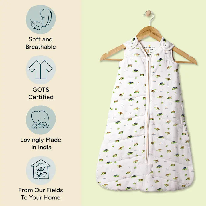 Nintara Baby sleep sack on a wooden hanger. Features icons highlighting soft and breathable fabric, GOTS certified organic cotton, lovingly made in India, and sourced from field to home.