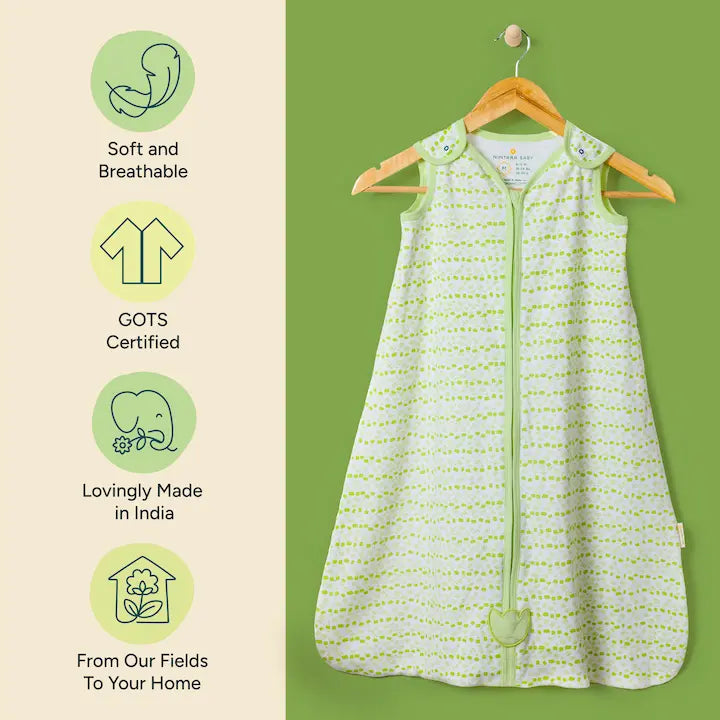 Nintara Baby sleep sack on a wooden hanger. Features icons highlighting soft and breathable fabric, GOTS certified organic cotton, lovingly made in India, and sourced from field to home.
