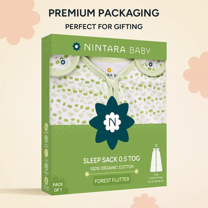 Cheerful baby on pink surface in Nintara Baby Forest Flutter sleep bag, size S. White fabric with lime green dot and dash print, green piping trim, and tulip appliqué at zipper base.