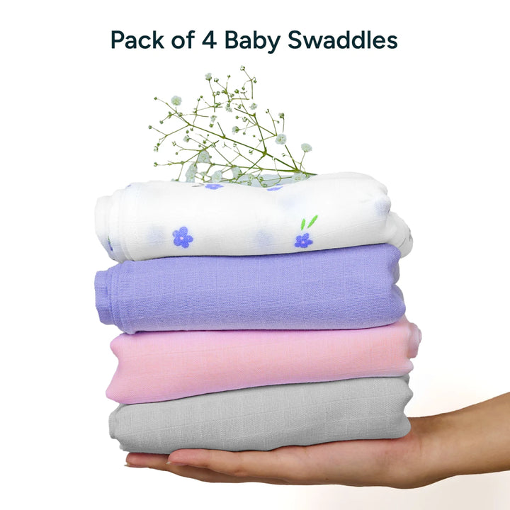 Stack of four baby swaddles in white with purple flowers and solid colors held in hand