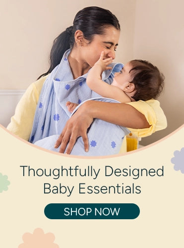 A mother lovingly wraps her baby in a soft muslin hooded towel featuring a blue stars print, holding the child close as they share a tender, joyful moment. She wears a light yellow outfit against a clean pastel background with playful floral shapes, alongside the text “Thoughtfully Designed Baby Essentials” and a prominent “Shop Now” call-to-action button.