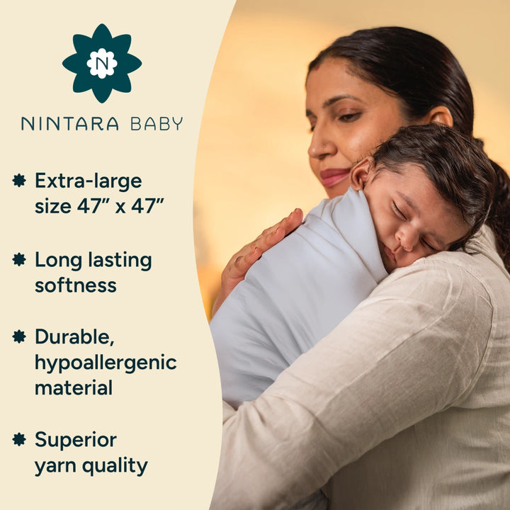 A mother gently holds her baby wrapped in a soft,blue organic cotton swaddle. The swaddle is extra-large (47” x 47”) for ultimate comfort and durability. Made from 100% organic cotton, it remains soft and gentle on the baby’s skin, even after multiple washes, unlike traditional cotton-blend swaddles which lose their softness over time.