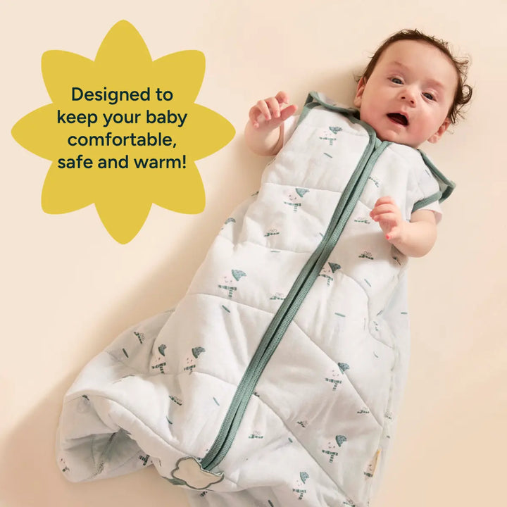 A baby is seen comfortably lying on their back, wearing the light blue Nintara Baby sleep sack. The sleep sack is soft, breathable, and designed to keep the baby cozy and secure. The baby's expression is curious as they gaze at the camera, while their tiny hand rests on the fabric. A bright yellow star-shaped graphic is positioned behind the baby The fabric design on the sleep sack features a subtle pattern of clouds and stars, providing a calm and soothing aesthetic.