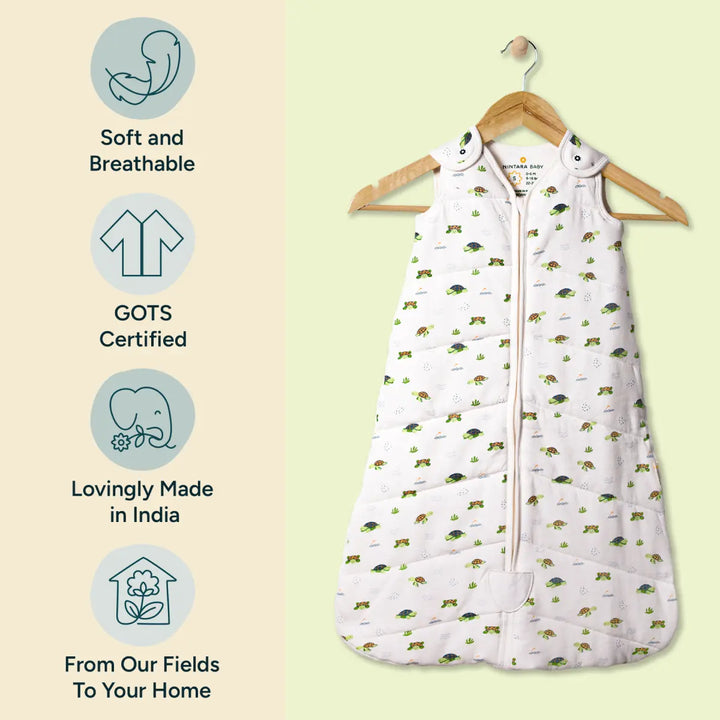 The Nintara Baby sleep sack is displayed hanging on a wooden hanger, highlighting its soft, breathable organic cotton fabric. The sleep sack features a whimsical turtle and plant pattern in soothing green tones. To the left of the product, three icons emphasize its key features: the product is soft and breathable, GOTS certified, and lovingly made in India. The design showcases the product's eco-friendly credentials while also highlighting its comfort and suitability for babies.