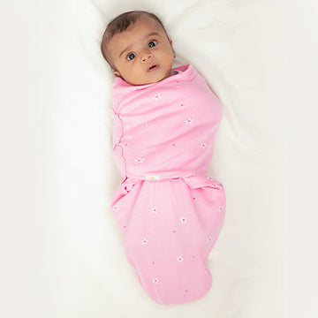 Baby wrapped in a pink wake me not swaddle on a white background